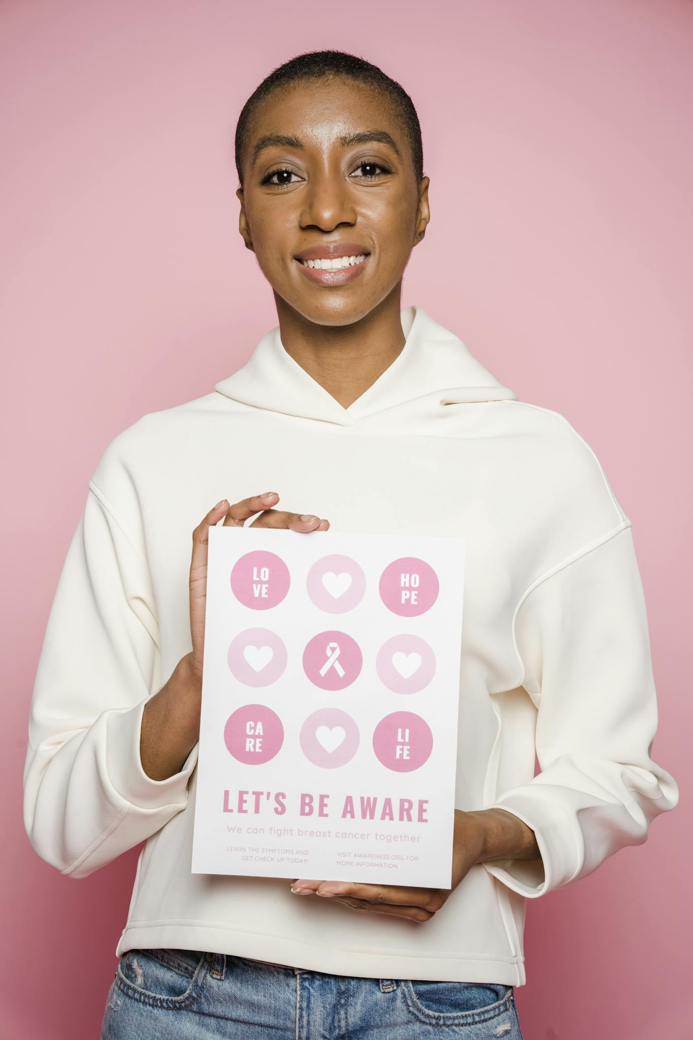 African American woman promoting breast cancer awareness with a motivational poster.